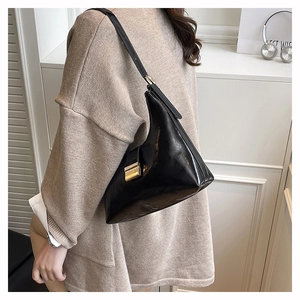 Detail of glossy black oil wax leather hobo bag with a square gold metallic buckle