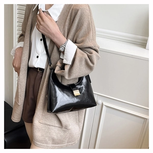 Close-up of black glossy hobo bag with gold hardware and magnetic buckle detail