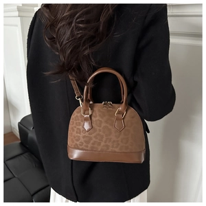 Detailed view of leopard print shell bag with golden zipper and leather handle