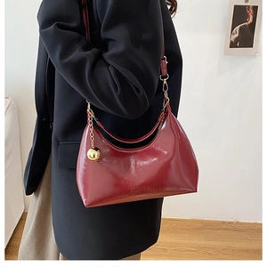 Détail du sac en cuir verni bordeaux montrant le gaufrage FASHION et le charme doré