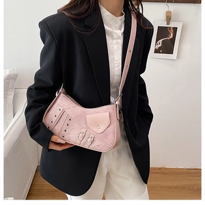 Detail of pink vintage faux leather saddle bag with metallic eyelets and buckle accents