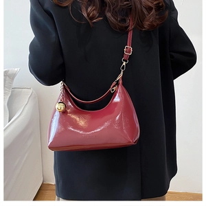 Vue détaillée du sac hobo en cuir verni rouge foncé avec un pendentif sphère dorée