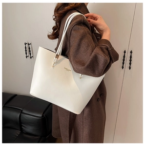 Close-up of minimalist white leather tote bag featuring elegant text print on the front