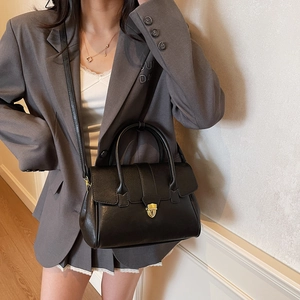 Classic black leather tote bag with gold lock buckle and top handle shown on a model