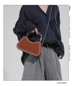 Sac à bandoulière en cuir marron avec rivets argentés et chaîne sur le mannequin