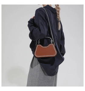 Sac à bandoulière élégant en cuir marron avec rivets porté par un mannequin