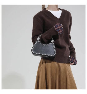 Détail du sac croissant noir avec clous argentés et poignée métallique sphérique