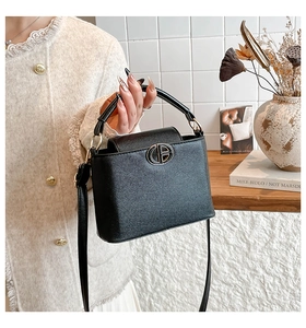Detail of black lychee grain leather bucket bag with gold hollow logo and smooth texture