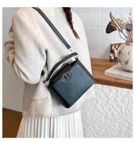 Detail view of the black crossbody bucket bag featuring a textured finish and metal buckle