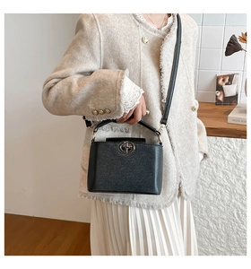 Close-up of black leather bucket bag with metal ring logo and elegant adjustable strap