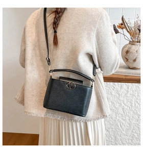 Detail of a black pebbled leather bucket bag shown on model with adjustable strap