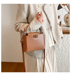 Detailed close-up of brown textured leather bucket bag with gold metal hardware and buckle