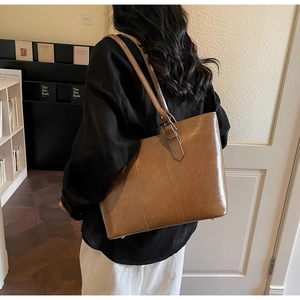 Detailed side view of a large brown leather tote bag with stylish adjustable shoulder straps