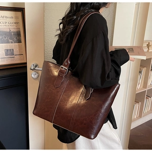Detail of a large vintage brown tote bag featuring contrast stitching and silver buckle