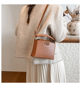 Close-up of brown litchi pattern leather bucket bag with circular metal hardware