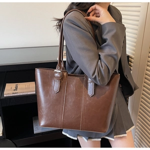 Detailed close-up of brown PU leather tote bag with vertical stitching and metal buckle
