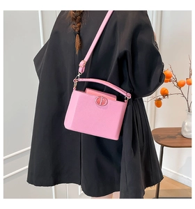 Lifestyle shot of pink PU leather bucket bag with metal buckle on black outfit
