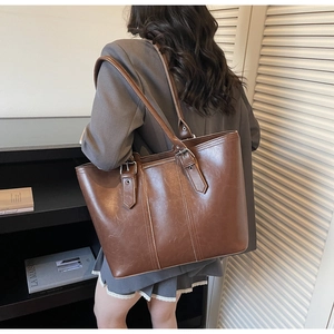 Detail of dark brown faux leather tote bag with metal buckle and spacious design