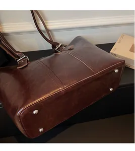 Close-up of durable handbag bottom with four metal protective feet on brown leather