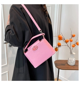 Pink leather bucket bag detail with round metal logo and detachable slim shoulder strap