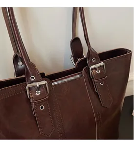 Macro detail of glossy oil wax leather texture and silver buckle on tote bag