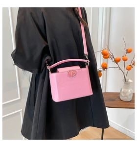 Pink crossgrain leather bucket bag held by model with elegant metal buckle detail