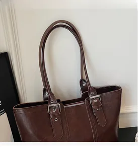 Detail of dark brown vintage leather tote with silver buckle and reinforced shoulder straps