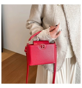 Detail of red pebbled leather bucket bag featuring a gold CB logo and handle