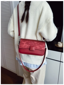 Dettaglio della borsa a tracolla rossa minimalista in pelle su maglione bianco