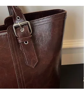 Detail of vintage brown leather tote bag showing adjustable strap and silver metal buckle