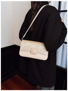 Dettaglio della borsa a tracolla in pelle beige testurizzata con fibbia magnetica quadrata su modella