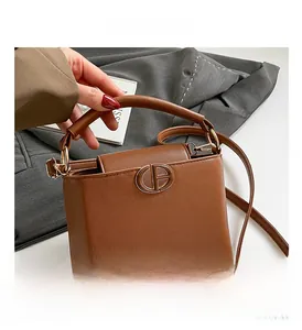 Close-up of brown litchi pattern bucket bag with golden hardware and adjustable strap