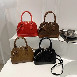 Chic leopard print shell handbags in four colors displayed on white geometric platforms