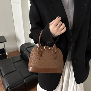Fashionable leopard print dome handbag with brown leather accents and gold hardware