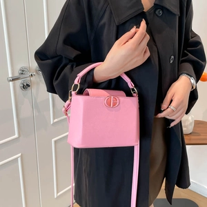 Chic pink bucket bag with gold circular buckle in a stylish urban lifestyle setting