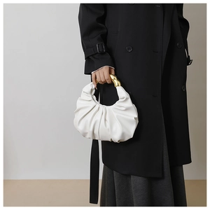 Détail du sac nuage plissé blanc avec poignée ergonomique en métal doré sur manteau noir