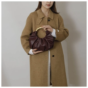 Gros plan d'un sac plissé marron foncé avec une poignée métallique en anneau doré
