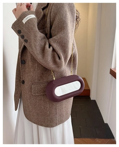 Detail of dark purple frosted crossbody bag with oval mirror and gold chain strap