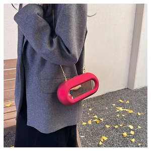 Detail of red irregular acrylic box bag with mirror inlay and gold chain strap