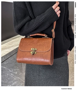 Detail of vintage brown leather handbag featuring intricate floral embossed patterns