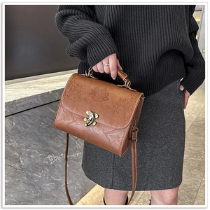 Detail of vintage brown leather bag featuring exquisite embossed floral patterns and metal lock