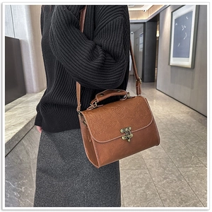 Detail of vintage brown crossbody bag with floral embossing and bronze hardware