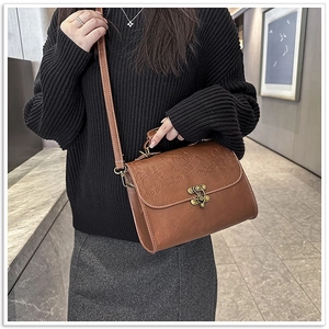 Close-up of vintage brown leather bag with embossed texture and antique bronze lock