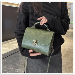 Detail of vintage green square handbag with floral embossing and bronze clasp