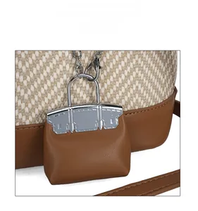Detail of a brown leather mini bag charm with silver hardware on a woven handbag