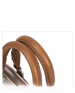 Detail view of reinforced stitching and silver metal hardware on brown leather handles