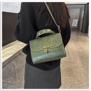 Detail of dark green vintage square bag with embossed lotus pattern and bronze metal lock