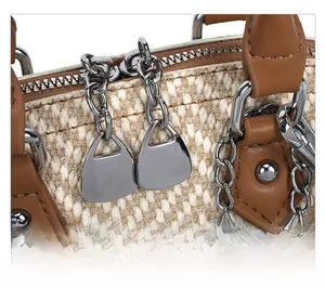 Detail of silver dual zippers and brown leather handle on a textured patchwork handbag