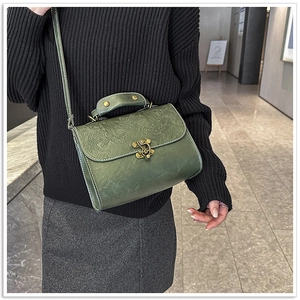 Detailed view of dark green retro square bag with exquisite floral embossing and bronze clasp