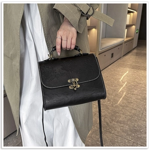 Detail of vintage embossed floral texture and contrast stitching on black crossbody bag
